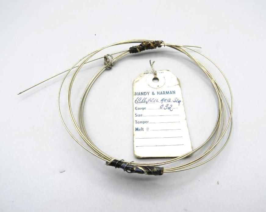 Coiled metal wires with attached tag. Tag text obscured, with