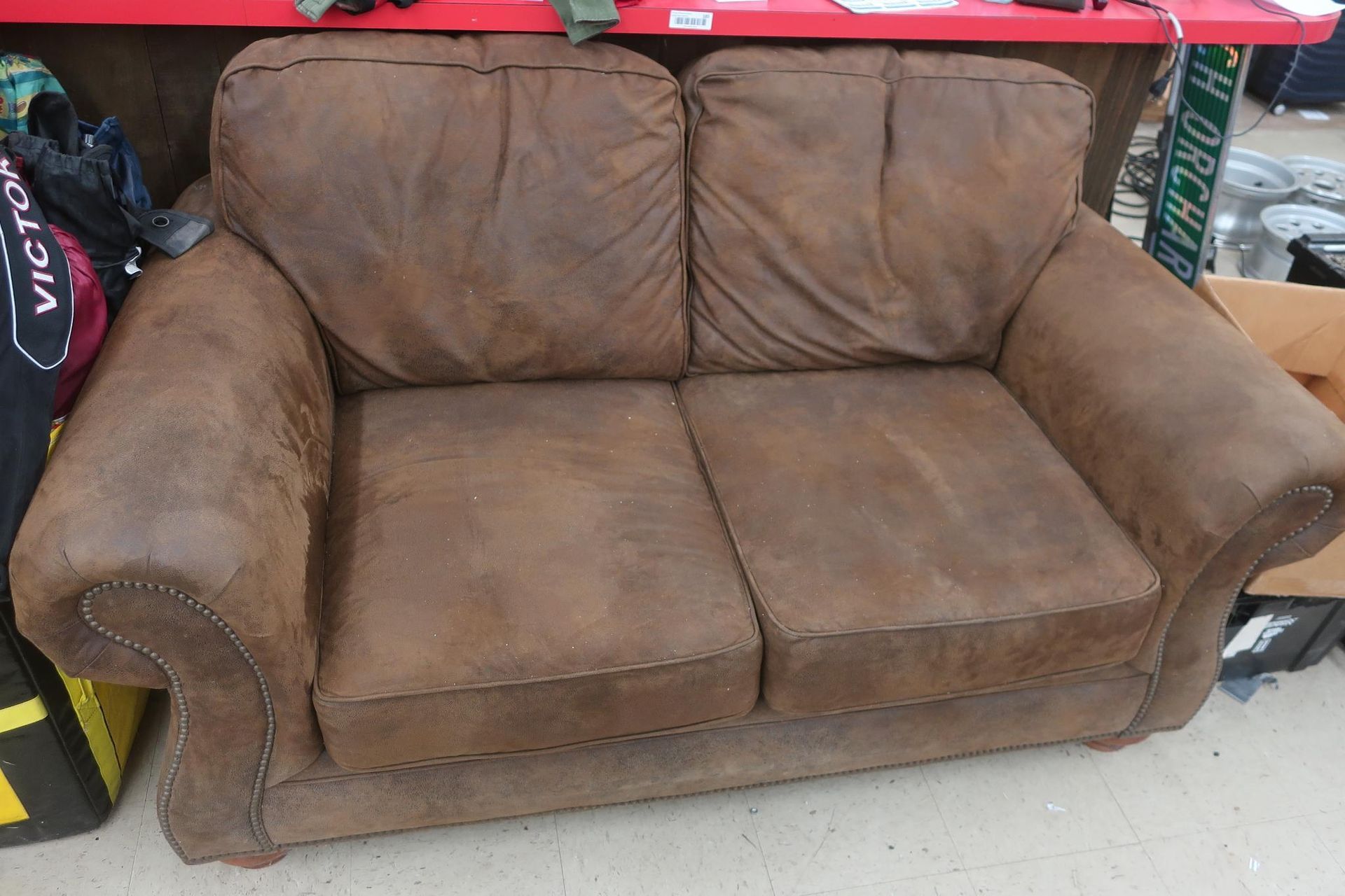Brown, two-seat sofa with a rustic appearance.
