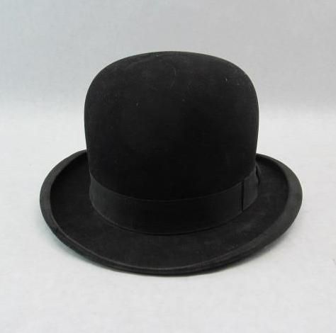 Black bowler hat with a curved crown and brim, set on a white surface.