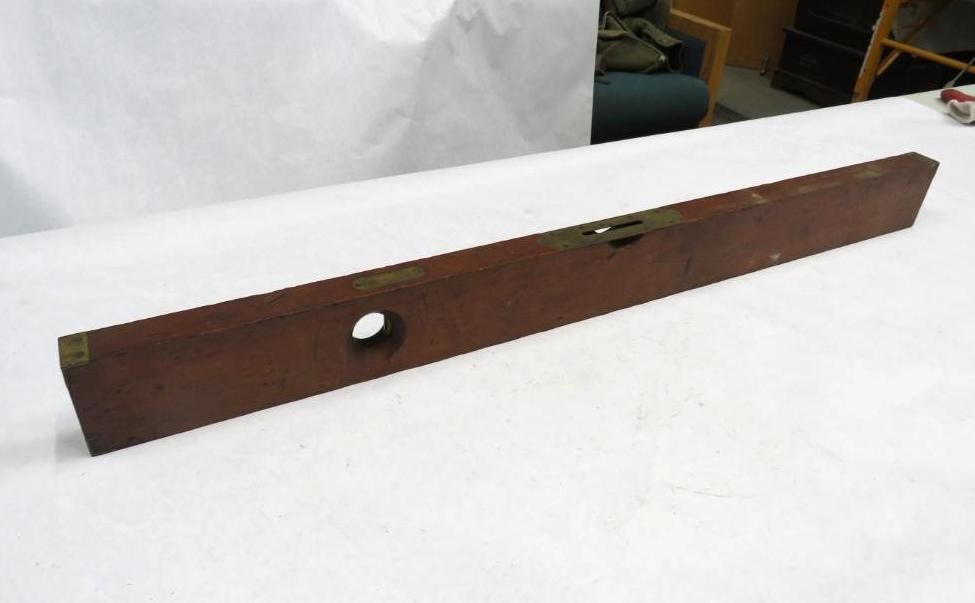 Brown wooden level tool with a circular hole, brass details, and bubble levels.