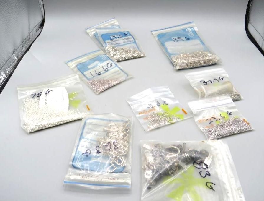 Assortment of small beads in sealed plastic bags. Bags vary in size and color, scattered on a light surface.