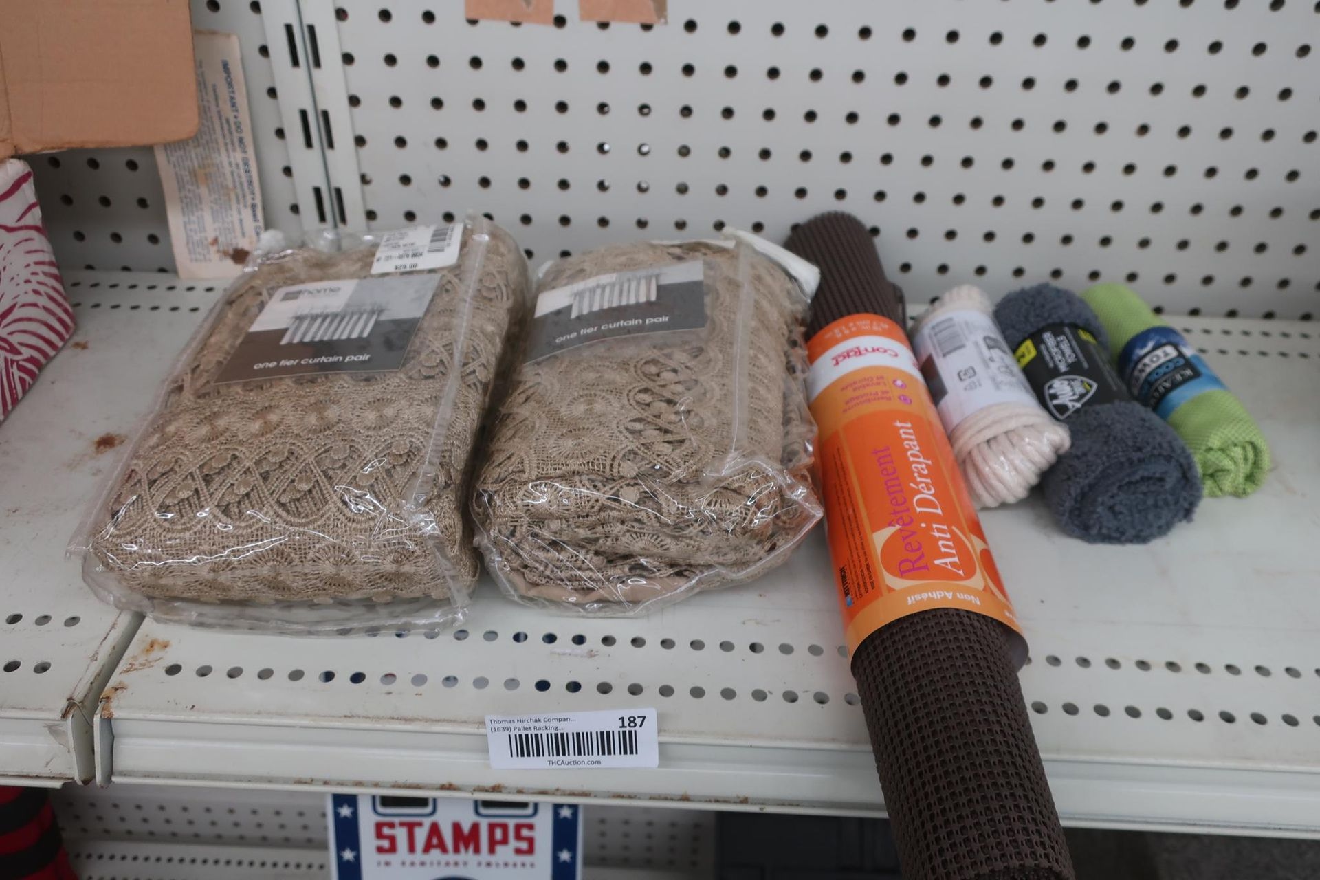 Two bags curtains and rolls of other materials on a store shelf.