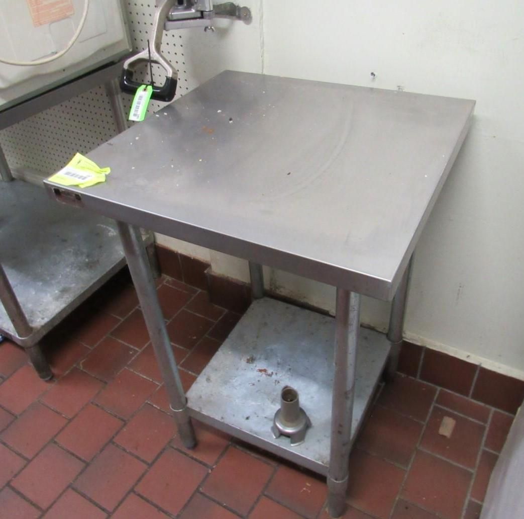 Stainless steel work table in a kitchen, with a lower shelf and red tile floor.