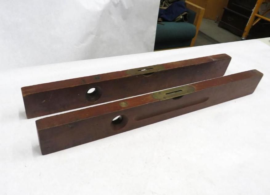 Two wooden levels with brass inserts lie on a white surface.