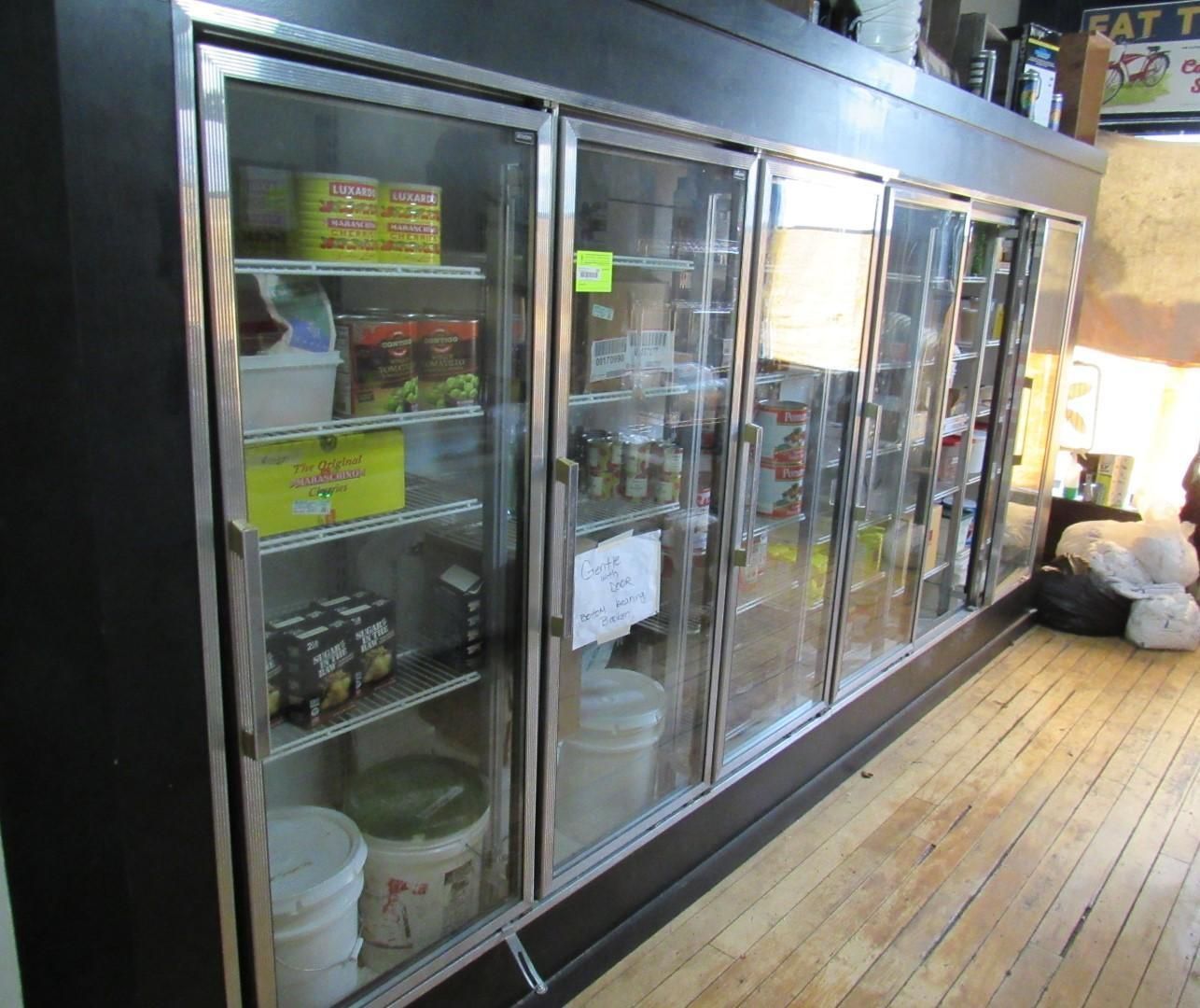 Large refrigerated display case in a store, filled with various products behind glass doors.