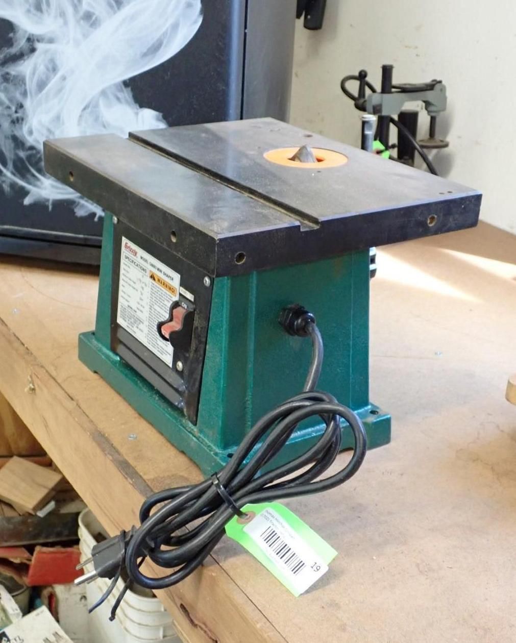 Green tabletop router with a black surface and power cord on a wooden surface.