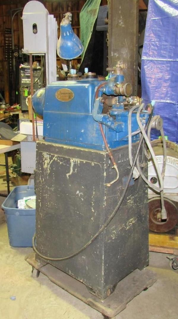 Blue and black industrial lathe on a stand in a workshop.