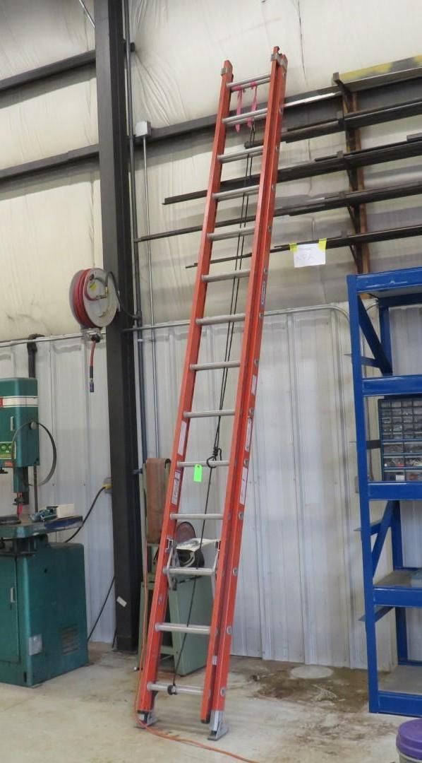 Red ladder leaning against a wall in a warehouse.