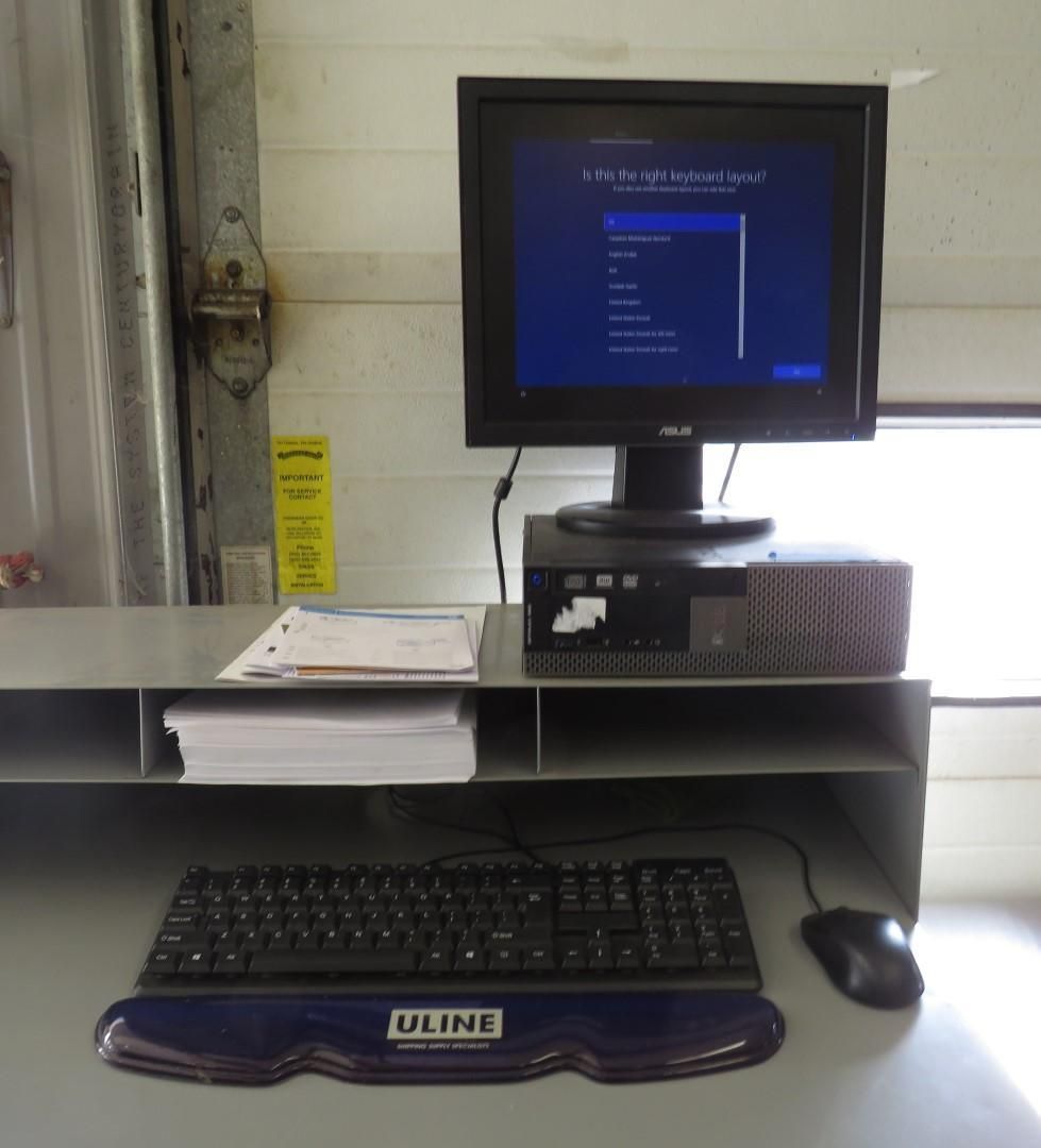 Computer setup on a desk with keyboard, mouse, monitor displaying a menu, and papers.