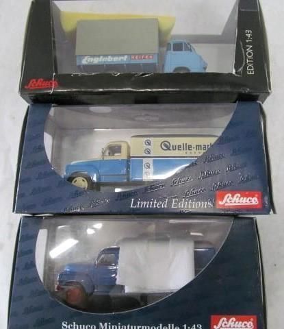 Three model trucks in boxes stacked, blue and white, with