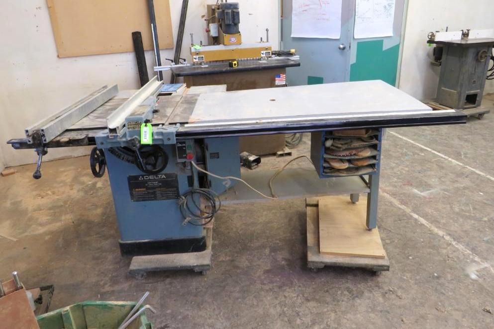 Blue table saw in a workshop with wood and other machinery in the background.