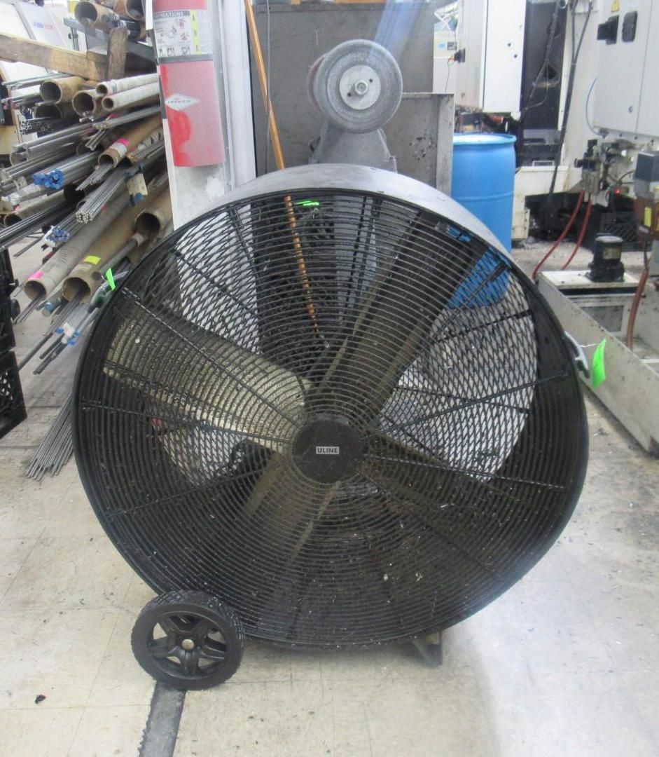 Large black industrial fan with wheels in a workshop.