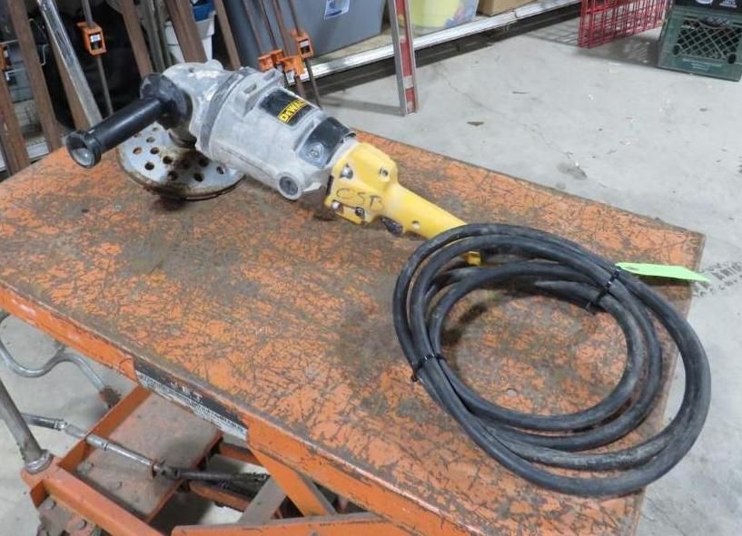 Angle grinder with a long black cord on an orange metal table.