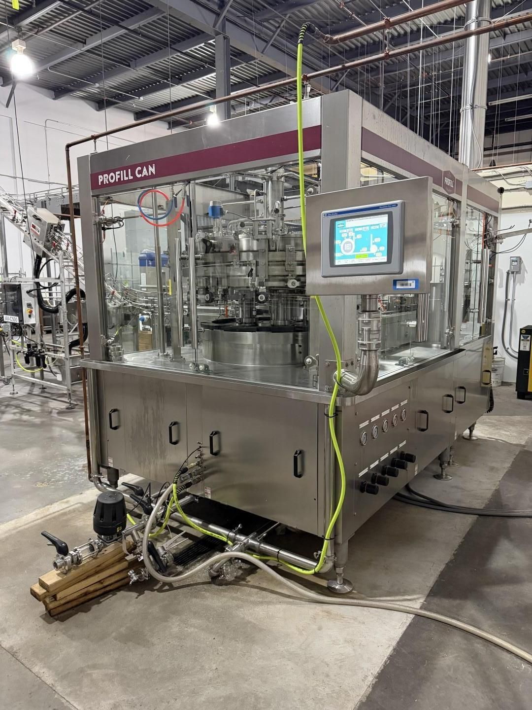 Industrial bottling machine with stainless steel components and a touchscreen interface.