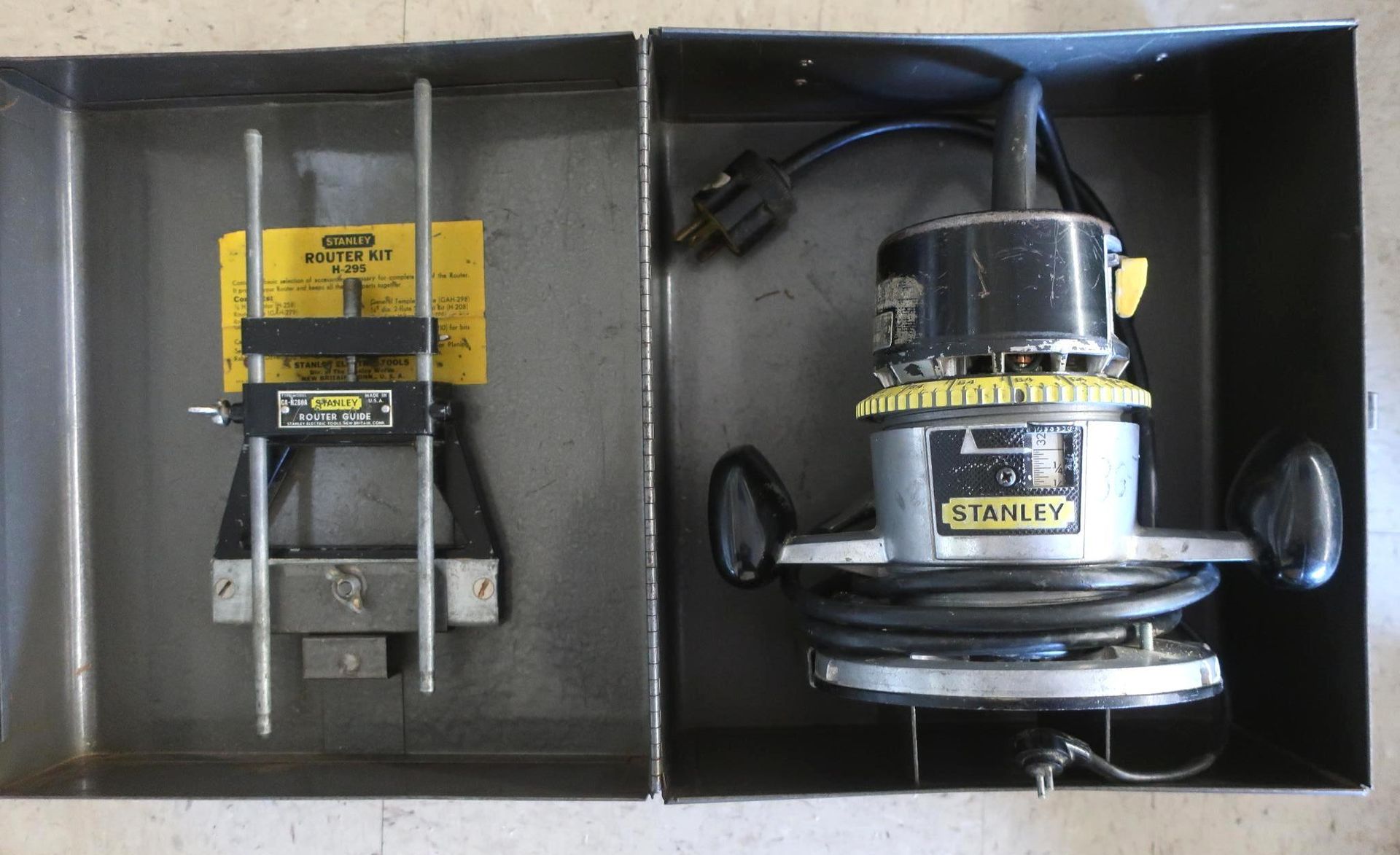 Two metal boxes; one contains a router, the other a guide assembly, both Stanley brand.