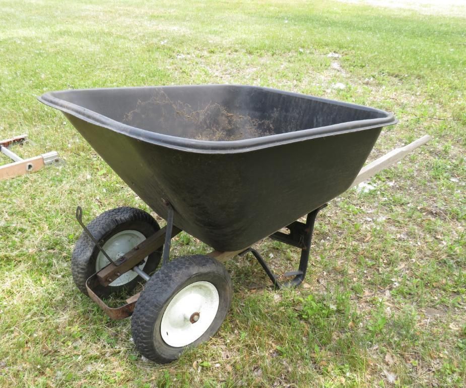 Black two-wheeled wheelbarrow on grass.