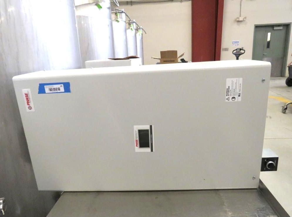 Large, gray electrical panel with a switch and labels on a metal surface in an industrial setting.