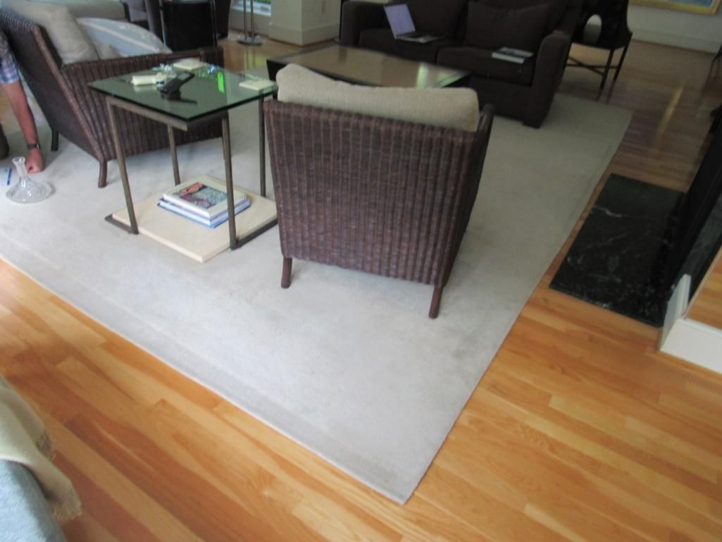 Living room with light-colored rug, brown wicker chairs, and wooden floor.