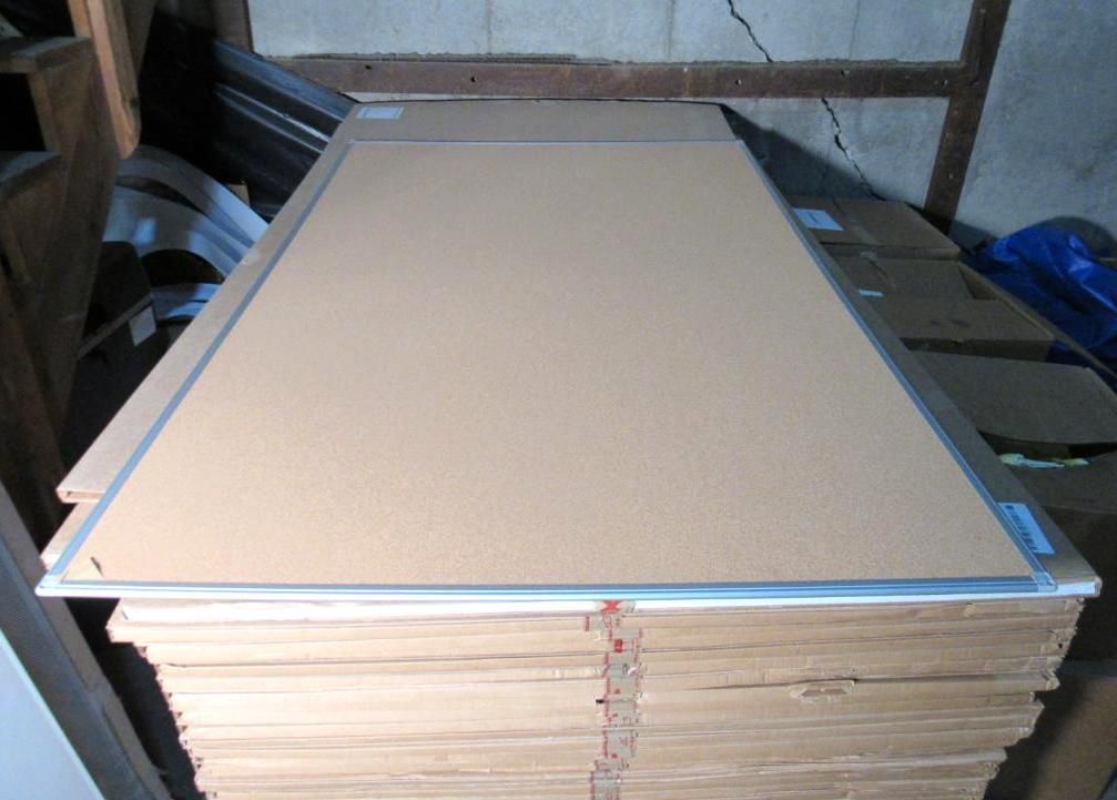 Stack of cardboard panels, tan with silver edging, in a storage area.