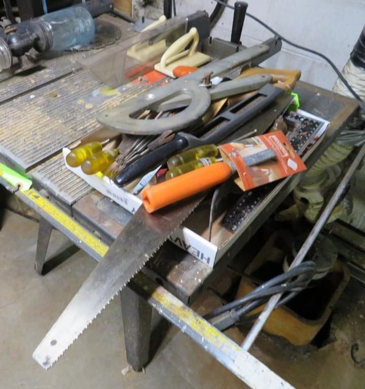 Workbench with saw, tools, and hardware. Metal surface, yellow tape measure, and gray table legs.