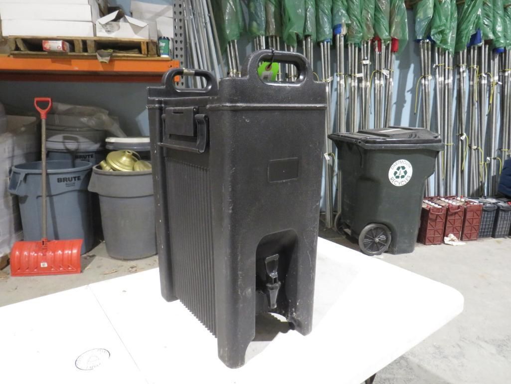 Black insulated beverage dispenser with spigot on a white table.