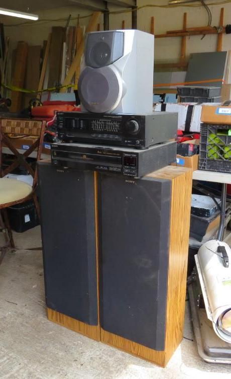 Stereo equipment stacked: two tall speakers, receiver, CD player, and a smaller speaker on top.