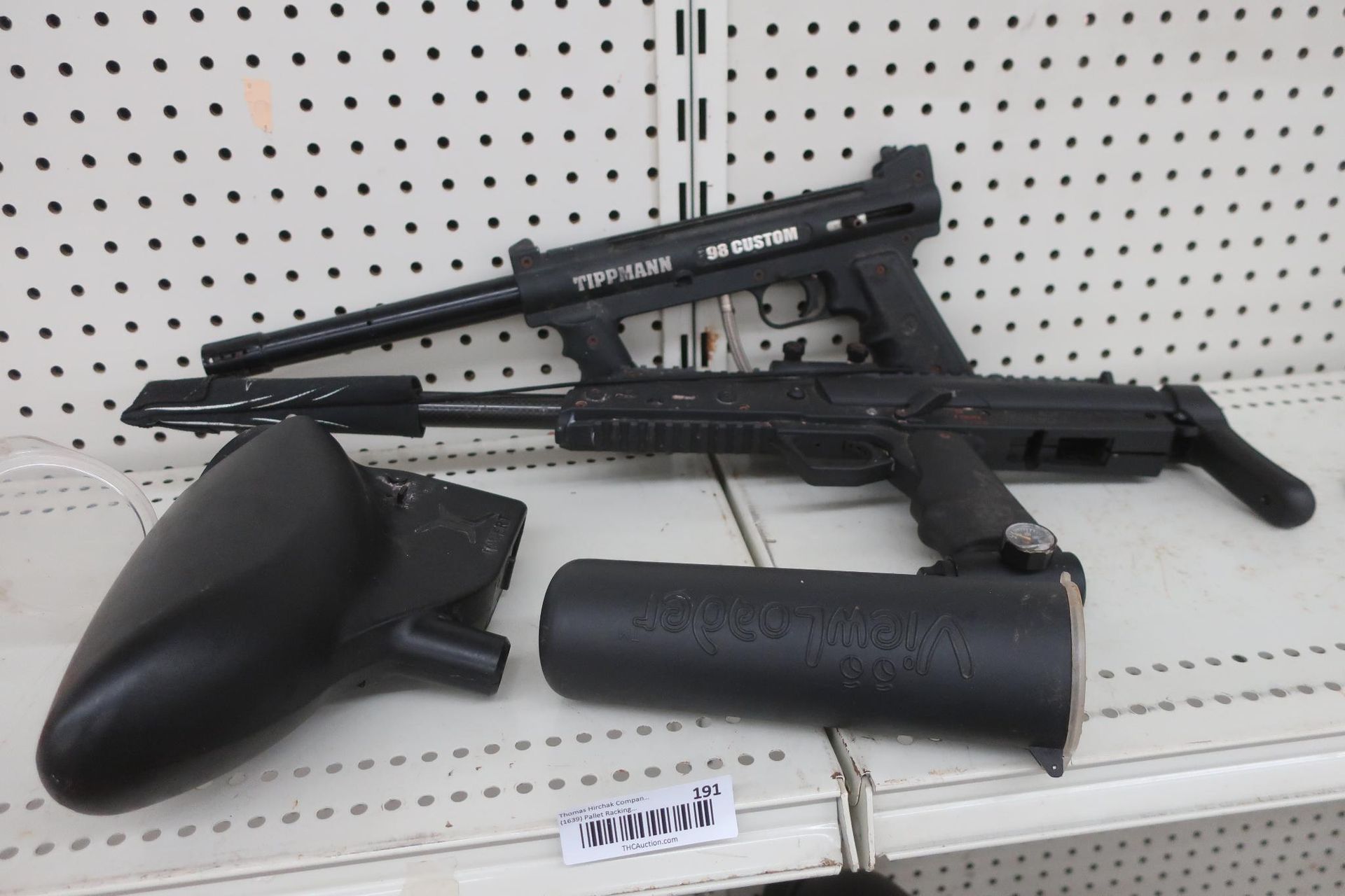 Black paintball guns and hopper on a shelf.
