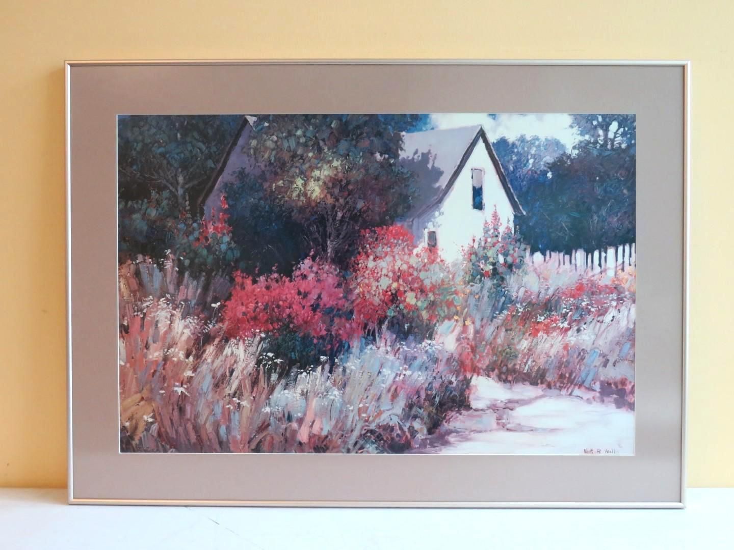 White house partially obscured by colorful flowers and foliage; framed art.