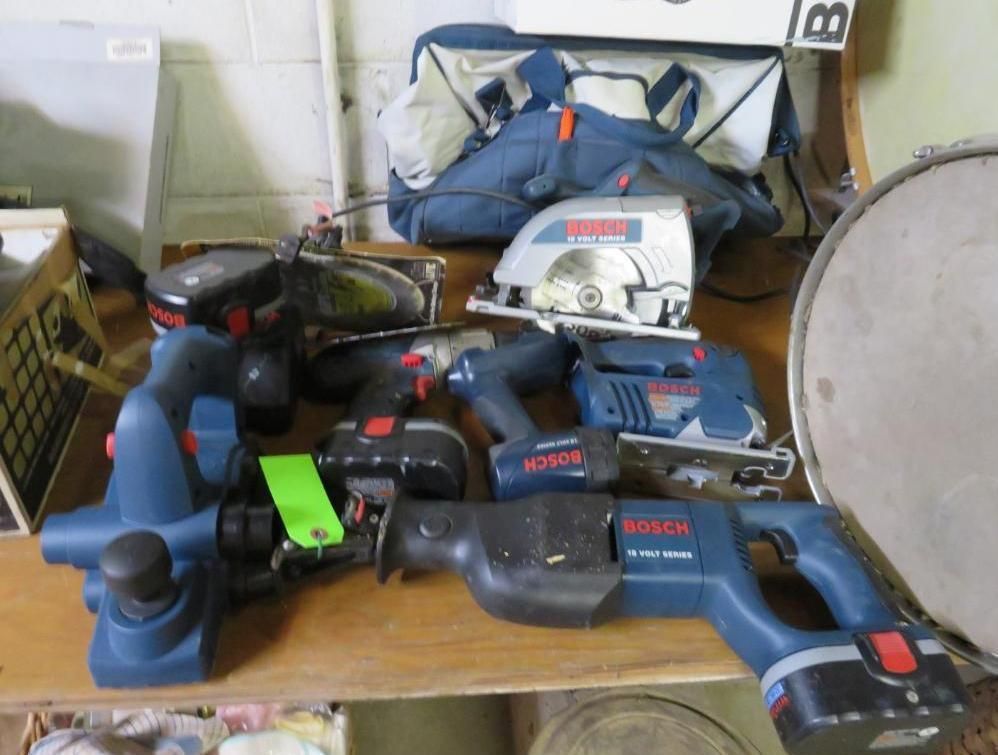 Collection of Bosch power tools on a wooden surface, including drills, saws, and a planer.