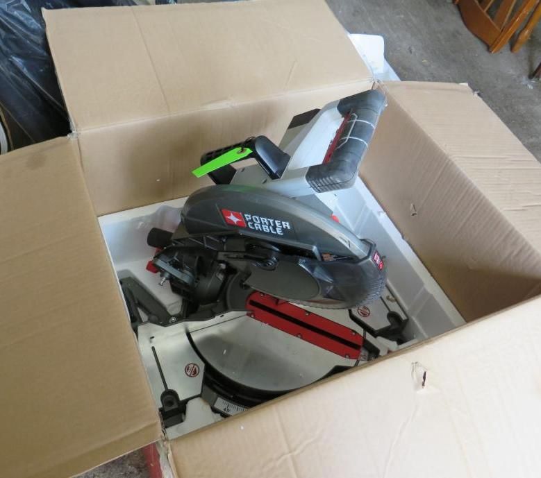 A miter saw in its cardboard packaging. The saw is gray and red and is cushioned by white foam.