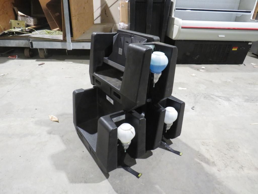 Black plastic portable sinks stacked, each with a blue or white soap dispenser.