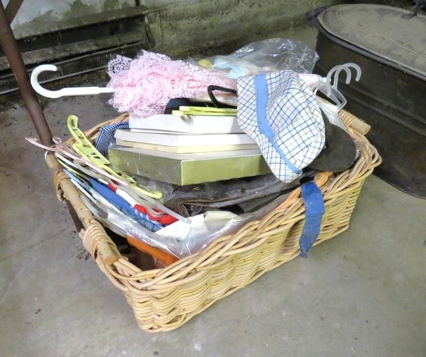 Wicker basket overflowing with miscellaneous items: hat, hangers, boxes, and fabric scraps.