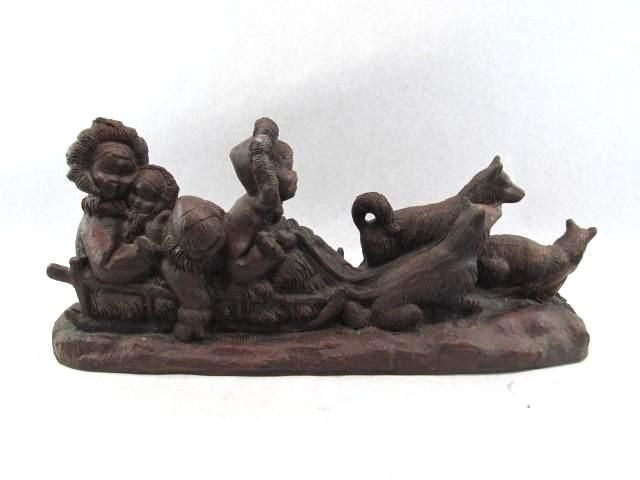 Brown figurine of people, dogs, and animals in a boat.