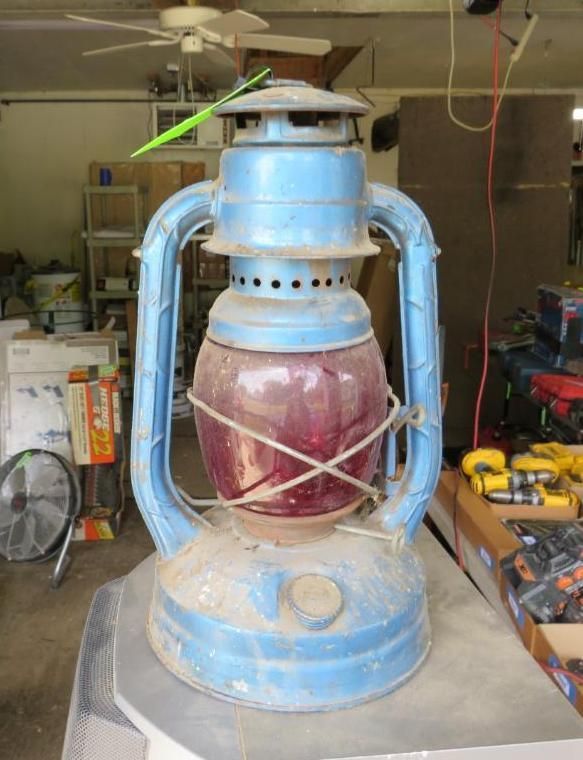 Blue and red vintage lantern with a worn appearance, sitting on a surface.