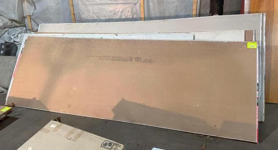Sheets of drywall stacked against a wall; a cardboard box sits in front.