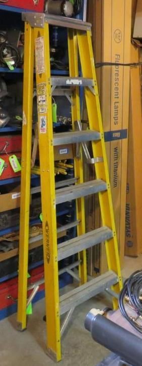 Yellow ladder leaning against a wall, in a storage area.