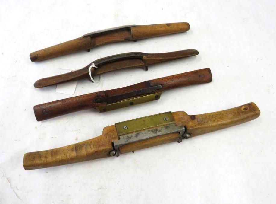 Four antique drawknives with wooden handles, arranged on a white surface.