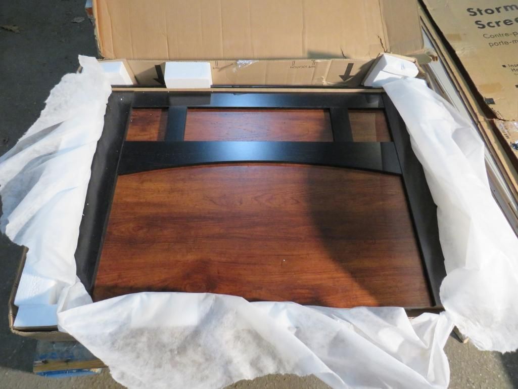 A wooden desk top with black metal frame, in cardboard packaging with white packing material.