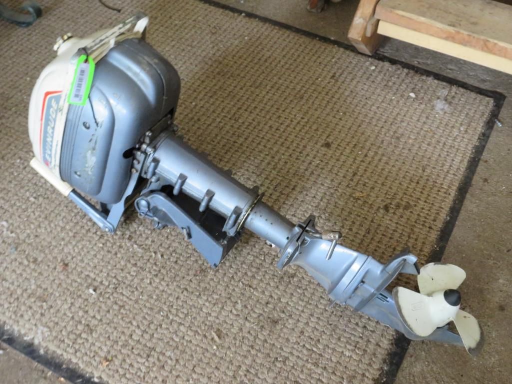 Gray and white outboard motor on a woven mat.