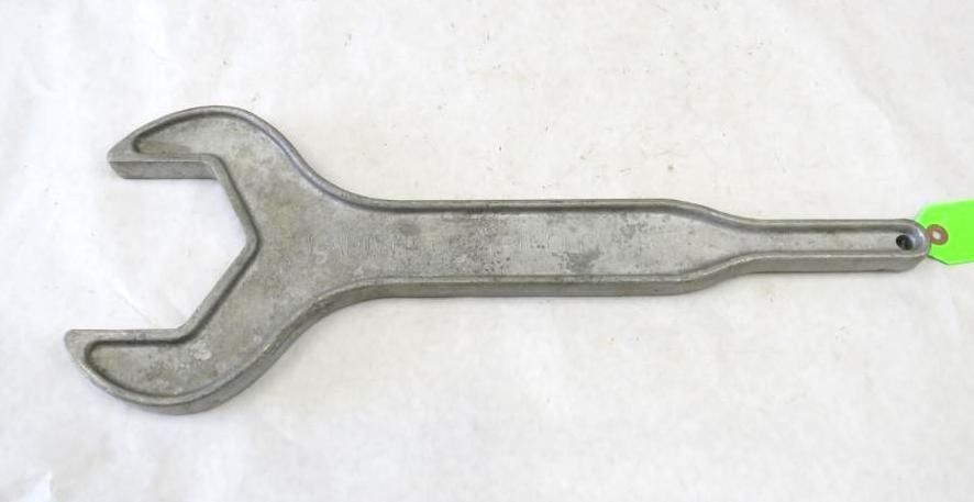 Silver spanner tool with open ends, lying on a white surface with a green tag attached.