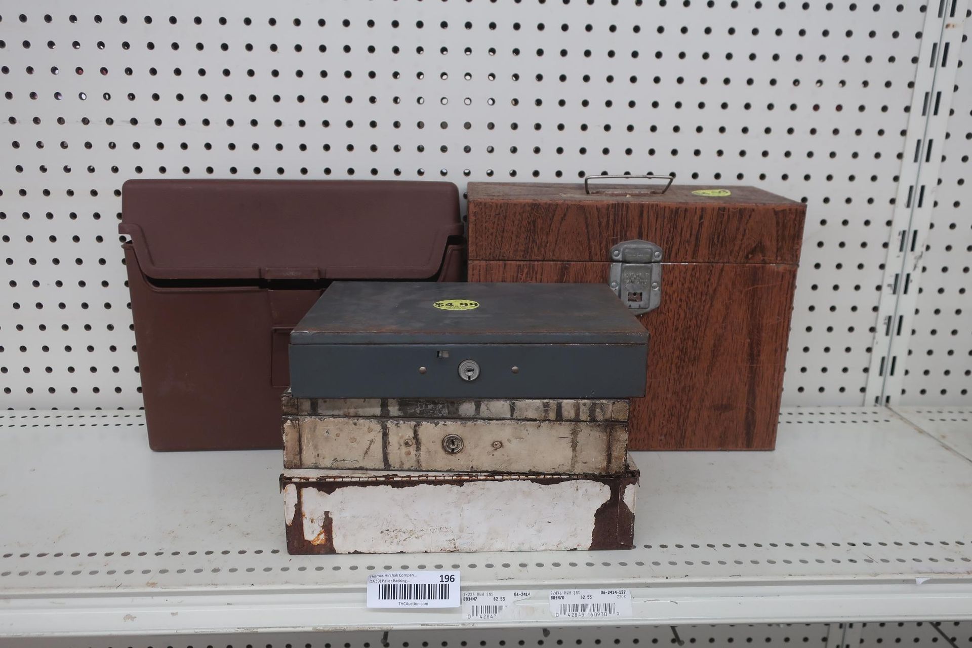 Three toolboxes on a shelf. Brown case, patterned box, and a gray metal one on a base.