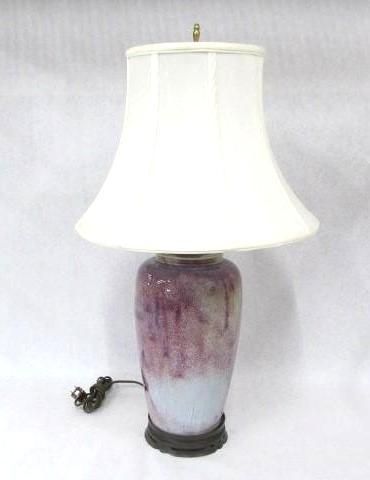 Purple and blue glazed ceramic lamp with white lampshade on a white surface.