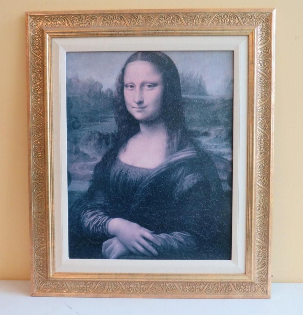 Mona Lisa painting in a gold ornate frame, featuring a woman with a slight smile, hands clasped.
