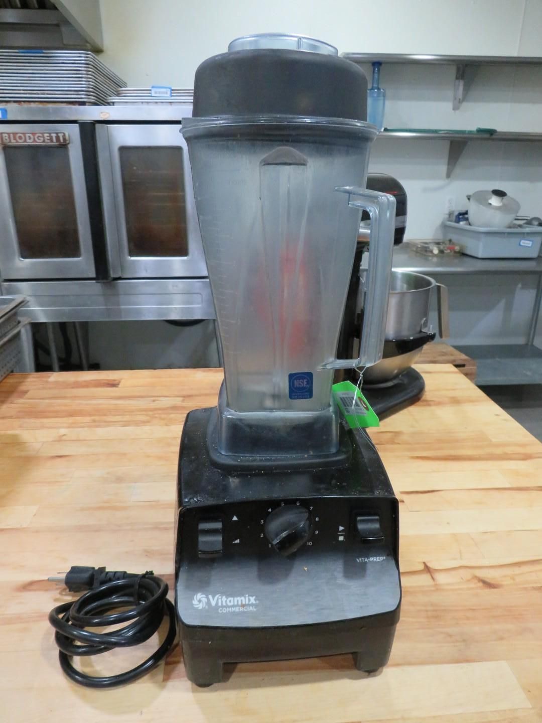 Black Vitamix blender on a wooden counter with a black power cord.