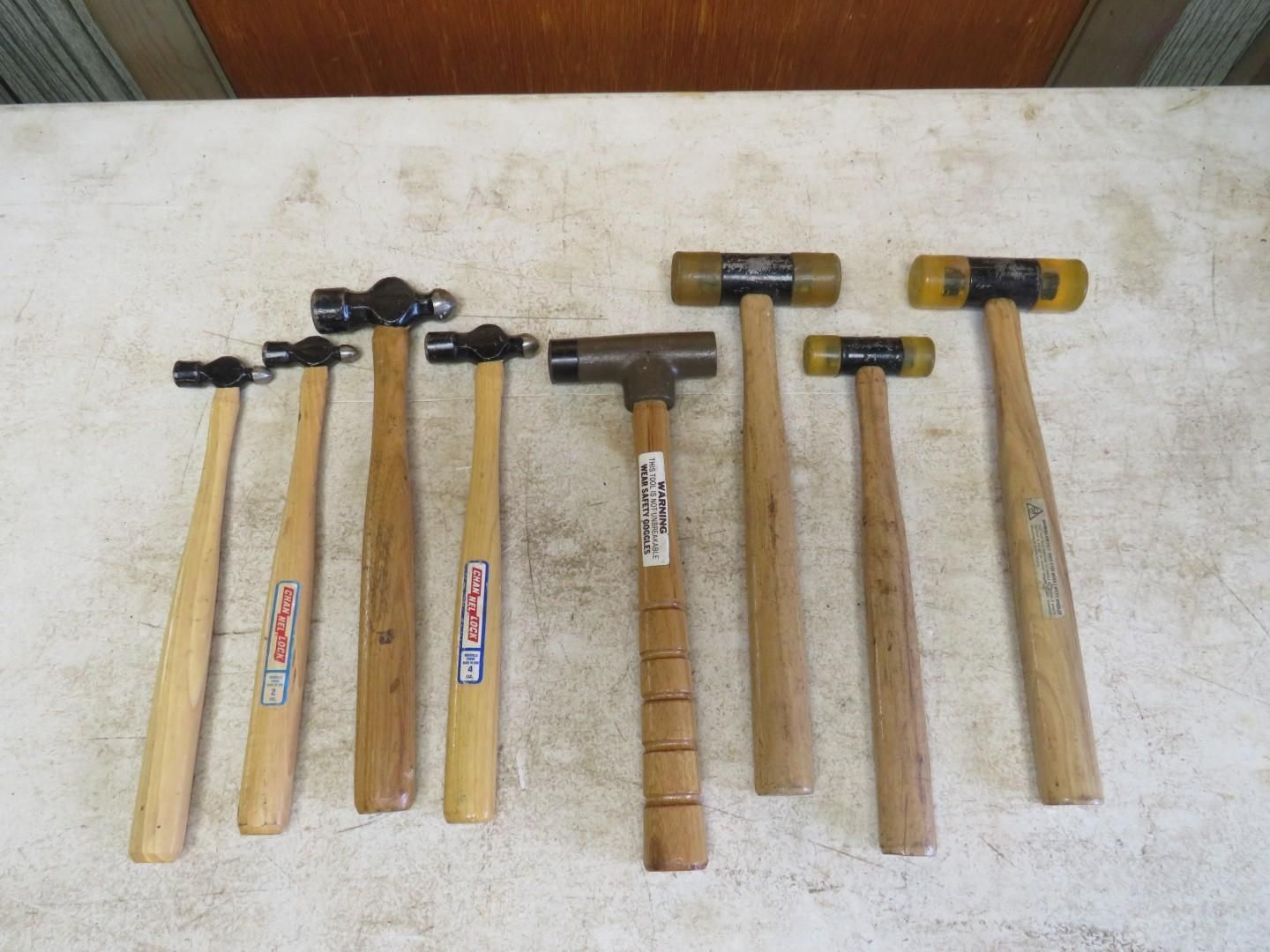 Collection of hammers with wooden handles and various heads, on a light-colored surface.