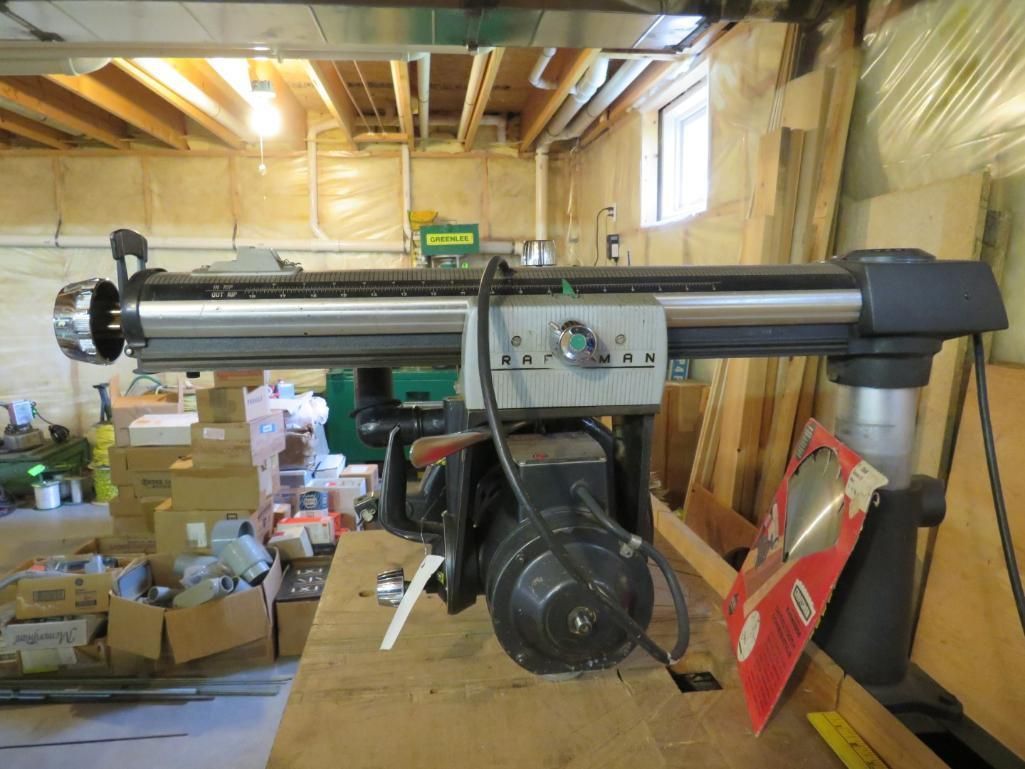 Radial arm saw on a wooden surface in a workshop setting. The saw is black with a silver arm.
