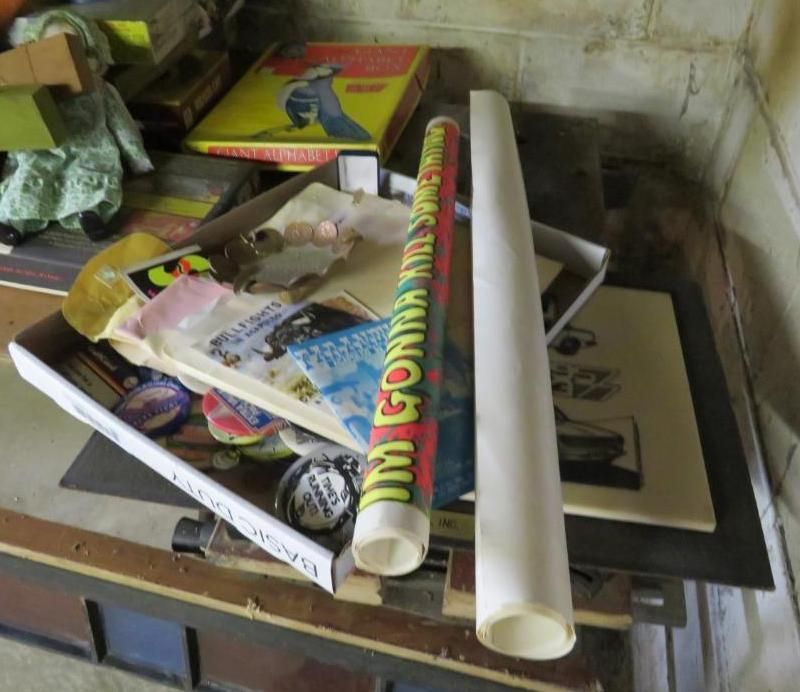Assorted items on a surface: a game box, tubes, papers, and small objects.
