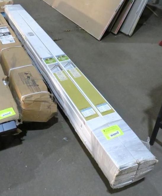 Bundled long white building materials on a pallet, possibly siding or trim.