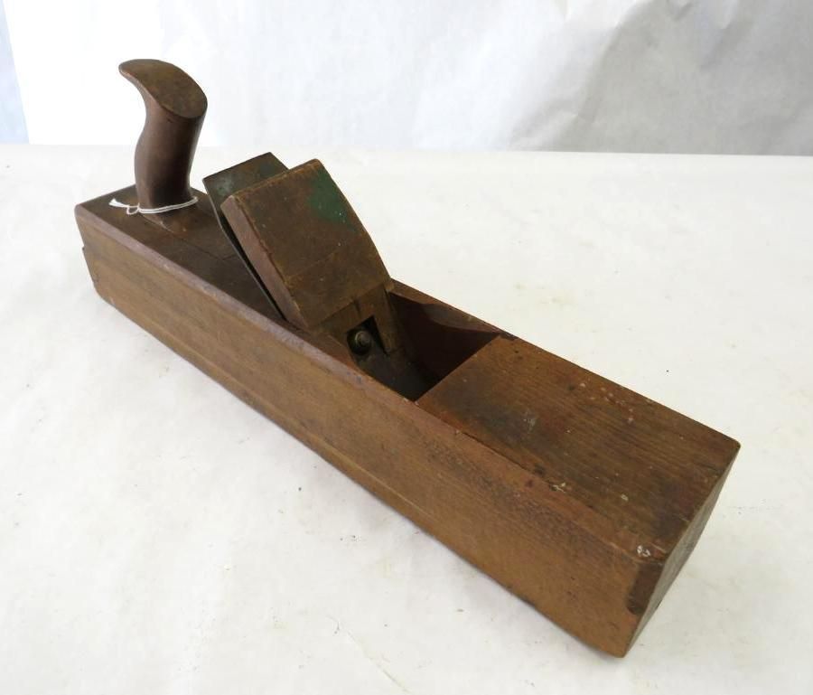 Wooden hand plane with a dark handle, on a white surface.
