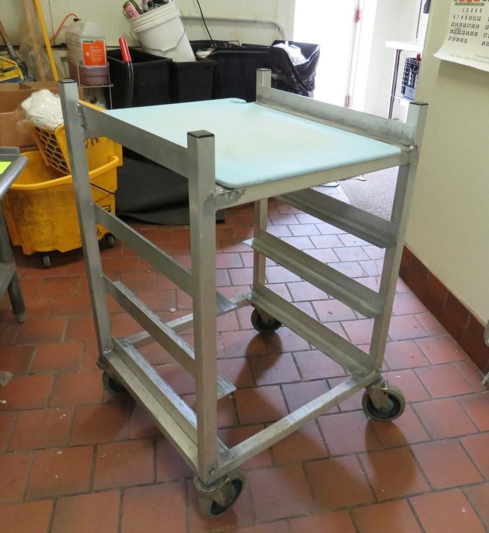 Metal utility cart with a cutting board top, on a tiled floor.